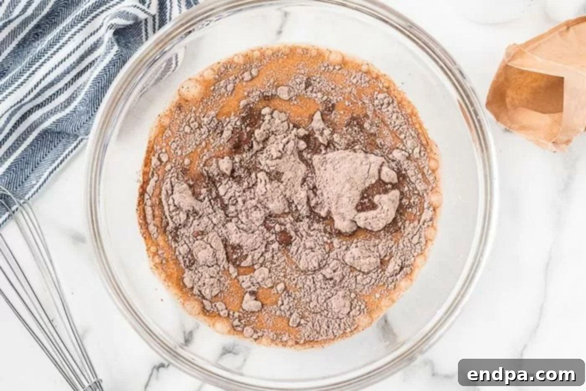 A separate mixing bowl where chocolate instant pudding mix is being whisked with cold milk until it thickens.