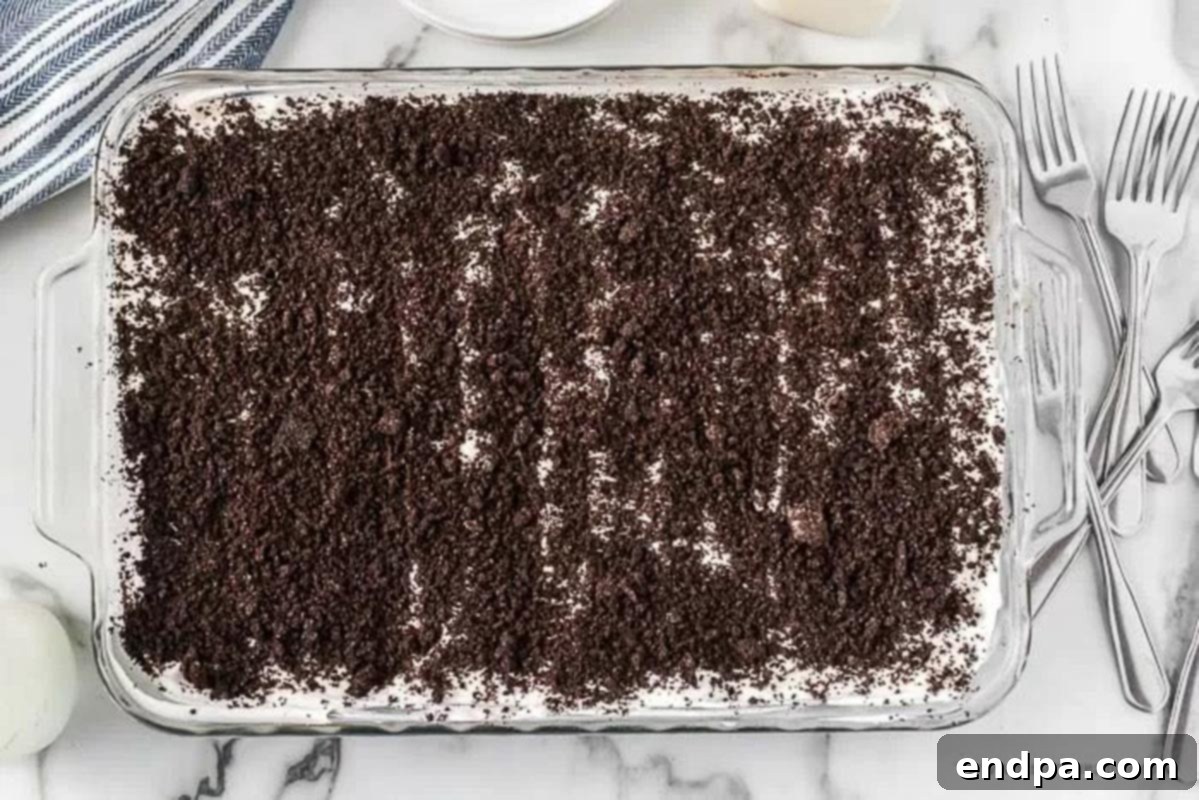 The final layer of whipped cream topped with reserved Oreo crumbs, ready to be chilled.