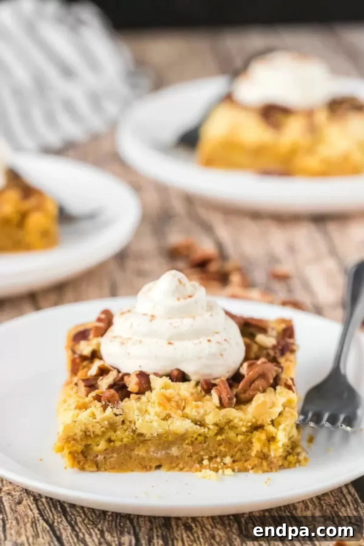 Delicious Pumpkin Pie Cake with Whipped Cream A slice of pumpkin pie cake topped generously with whipped cream, sitting on a plate.