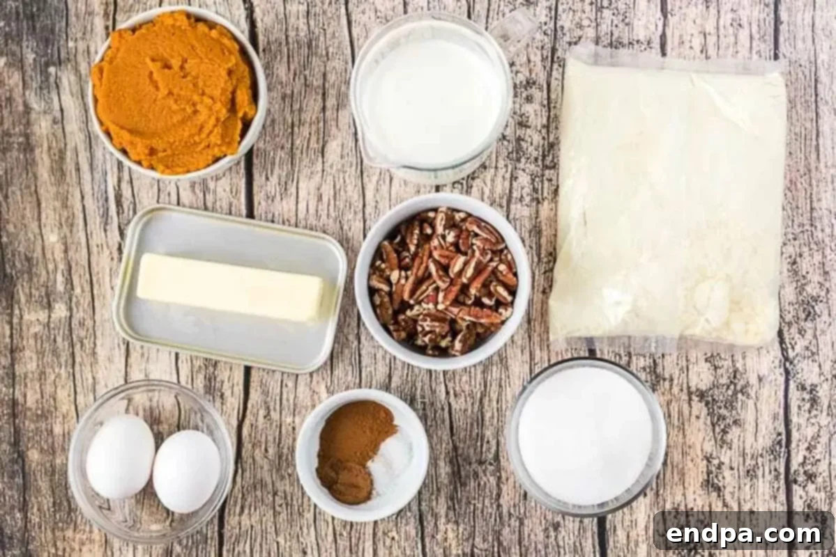 Pumpkin Pie Cake Ingredients A flat lay of ingredients for pumpkin pie cake: canned pumpkin puree, evaporated milk, sugar, cinnamon sticks, pumpkin pie spice, a yellow cake mix box, and a bowl of chopped pecans.