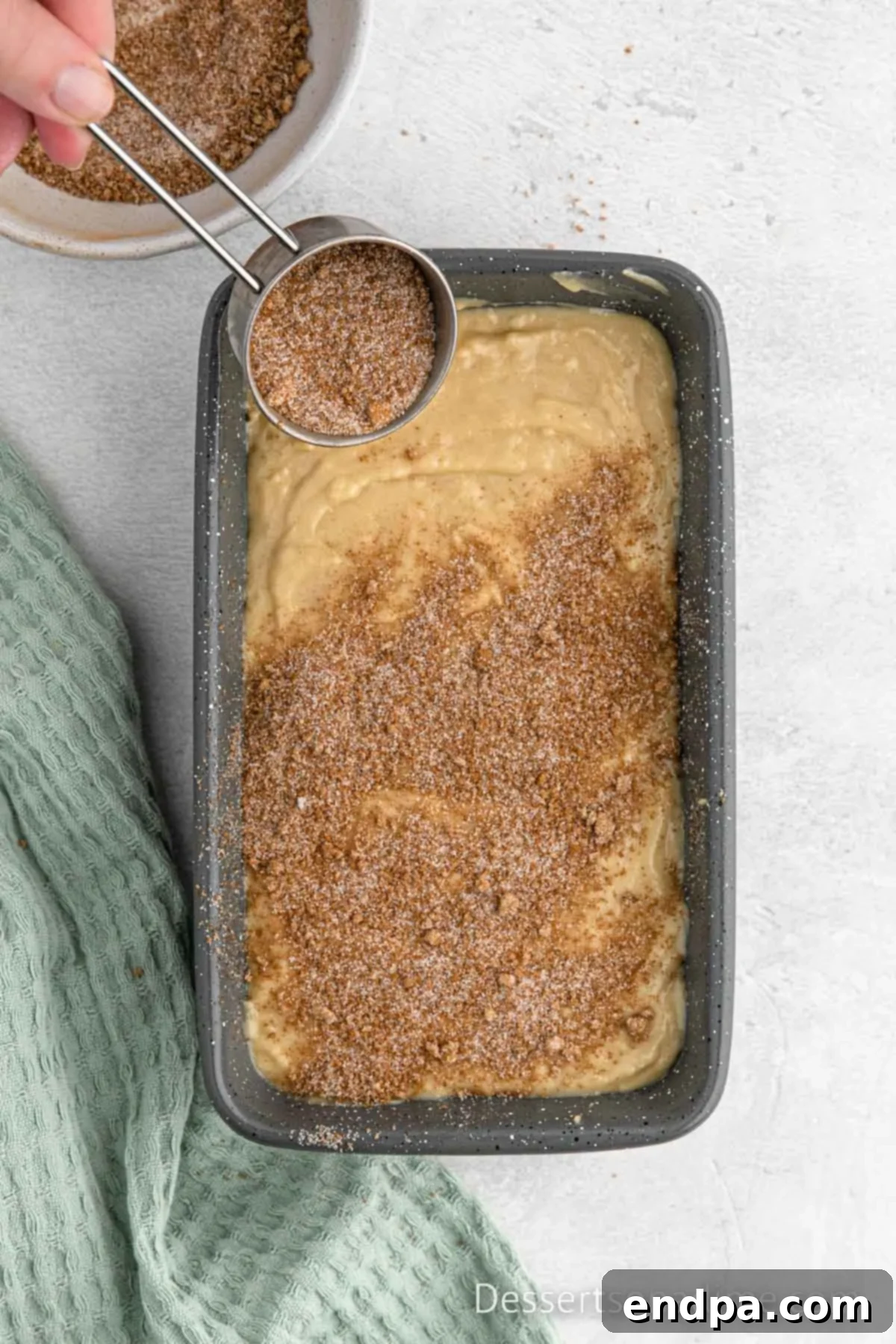 Loaf pan with a layer of cinnamon sugar mixture sprinkled over the bread batter.