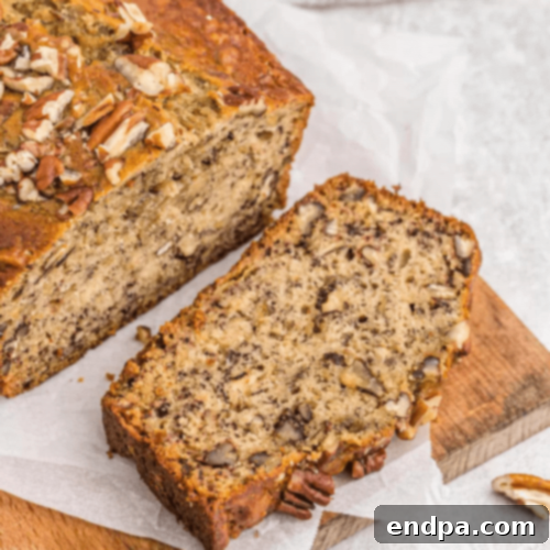 Sliced Banana Pecan Bread on a wooden cutting board with a knife.