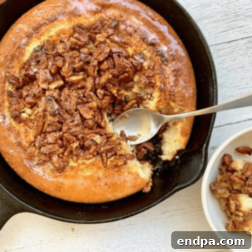 Pecan Pie Cobbler in a cast iron skillet, golden brown and bubbling.