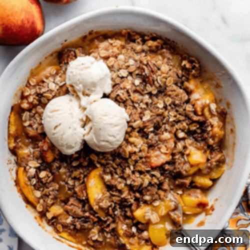 Pecan Peach Crisp in a baking dish, with a scoop of ice cream.