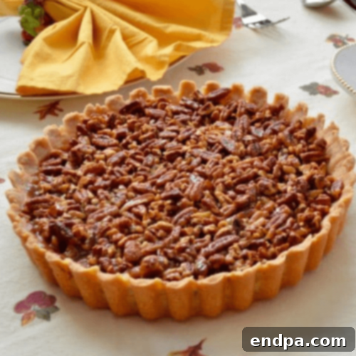 Caramel Pecan Tart slice on a white plate, garnished with whipped cream and a pecan.