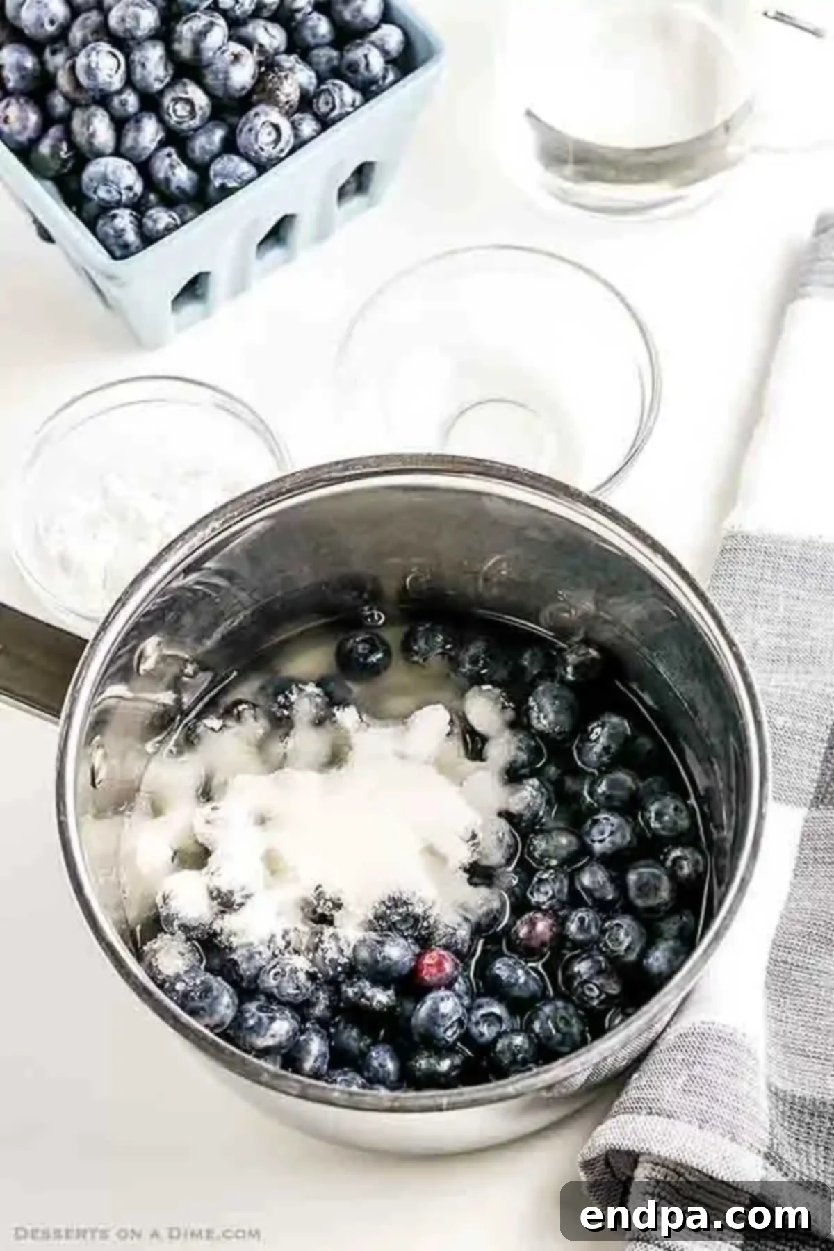 Saucepan of blueberries and sugar with water and lemon juice. 