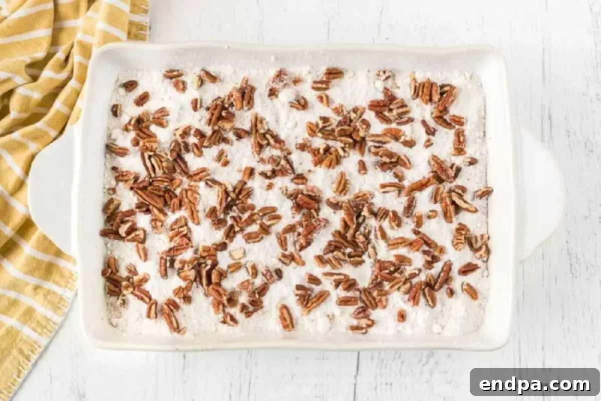 Dry cake mix spread over the pumpkin batter, with chopped pecans sprinkled on top.
