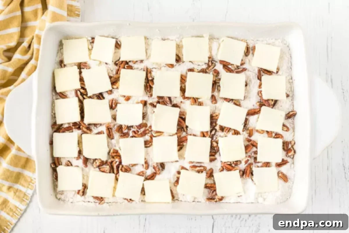 Thin slices of butter meticulously placed over the cake mix and pecans.