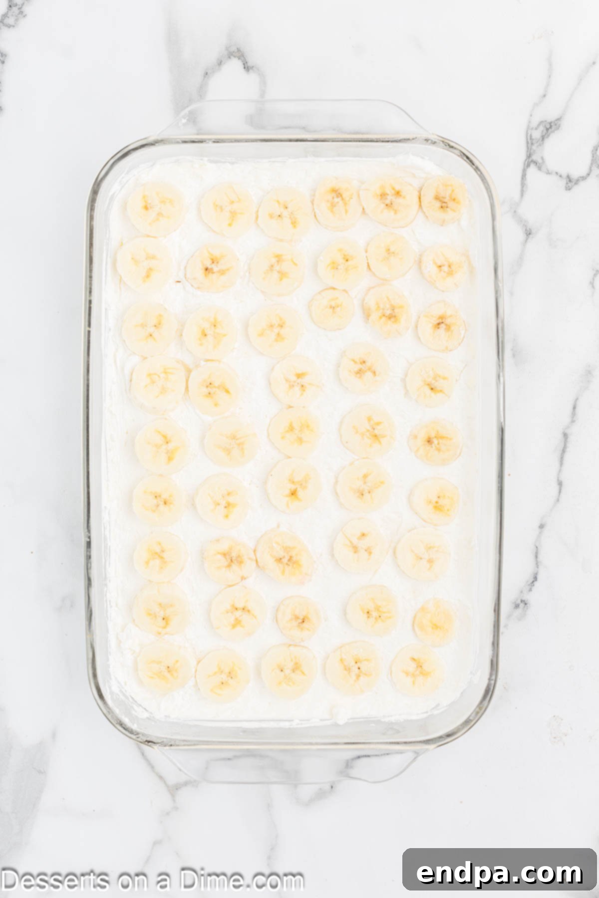 Banana Split Dream Cake 4 A layer of sliced bananas meticulously arranged over the creamy cream cheese filling in the baking dish.