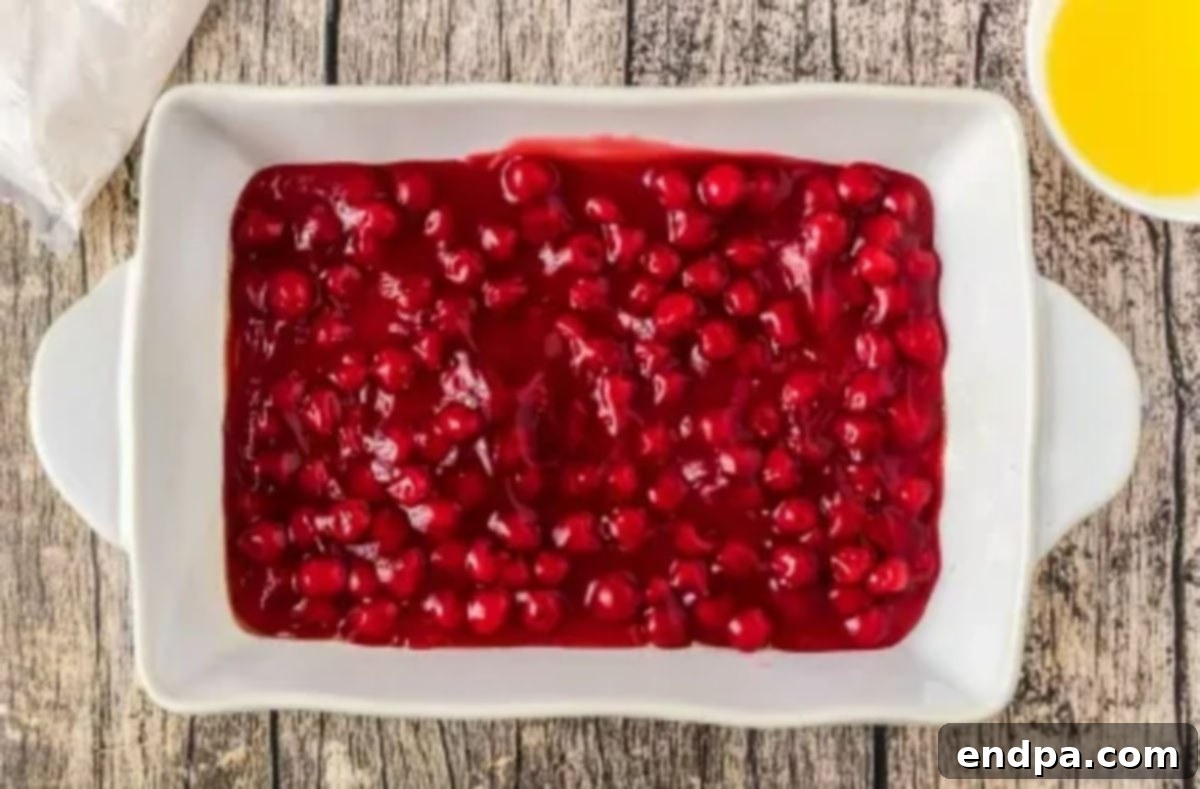 A 9x13 inch baking dish prepared with cooking spray and filled with two cans of cherry pie filling.