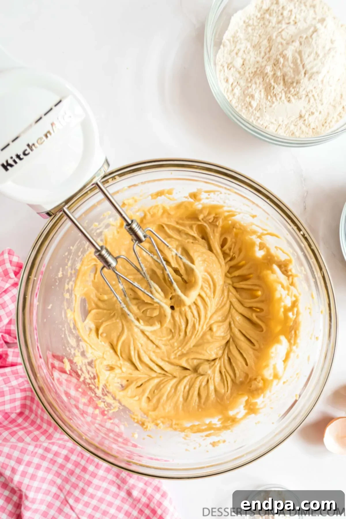 Egg and vanilla extract being added to the creamed butter and sugar mixture.
