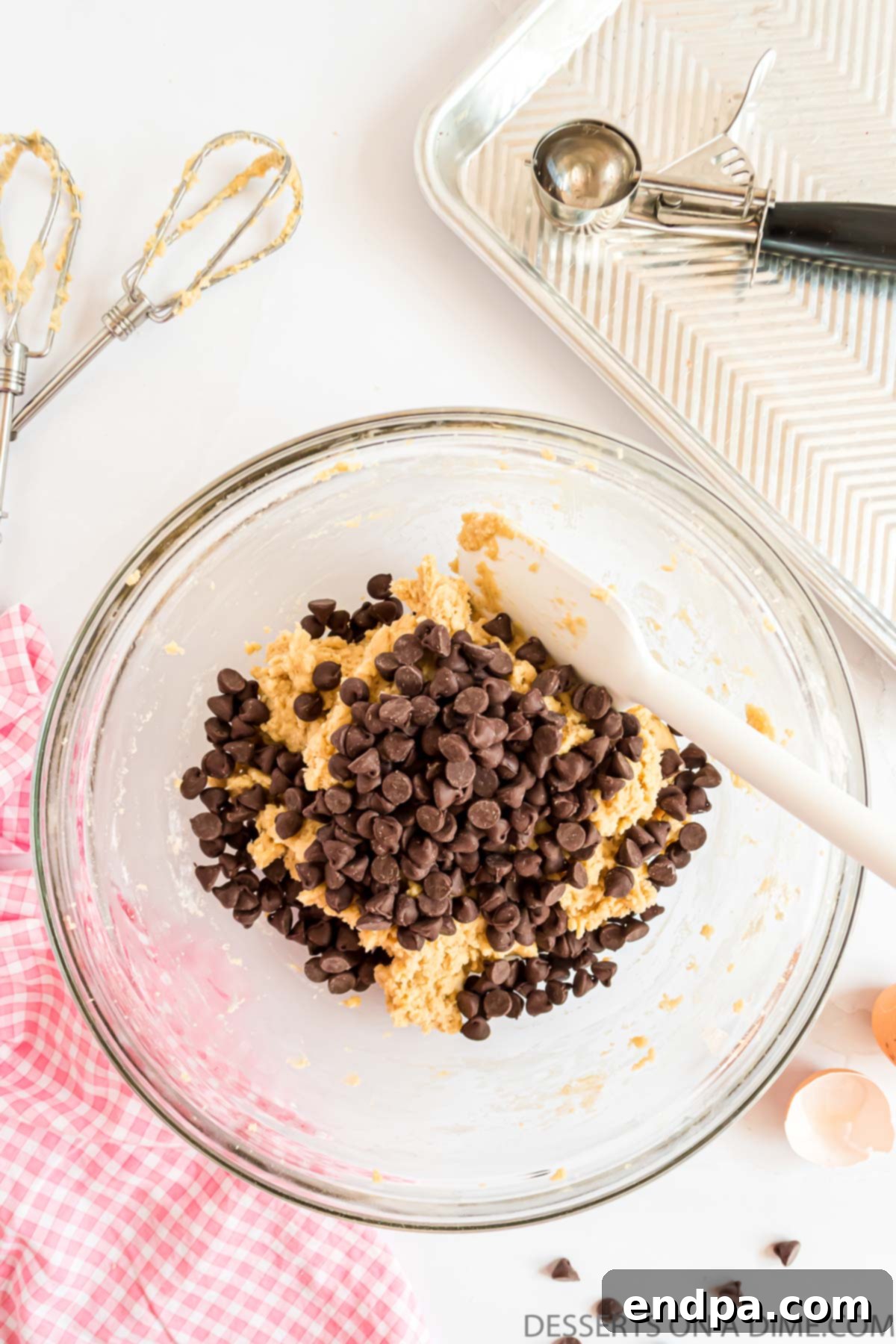 Semi-sweet chocolate chips being gently folded into the cookie dough by hand.