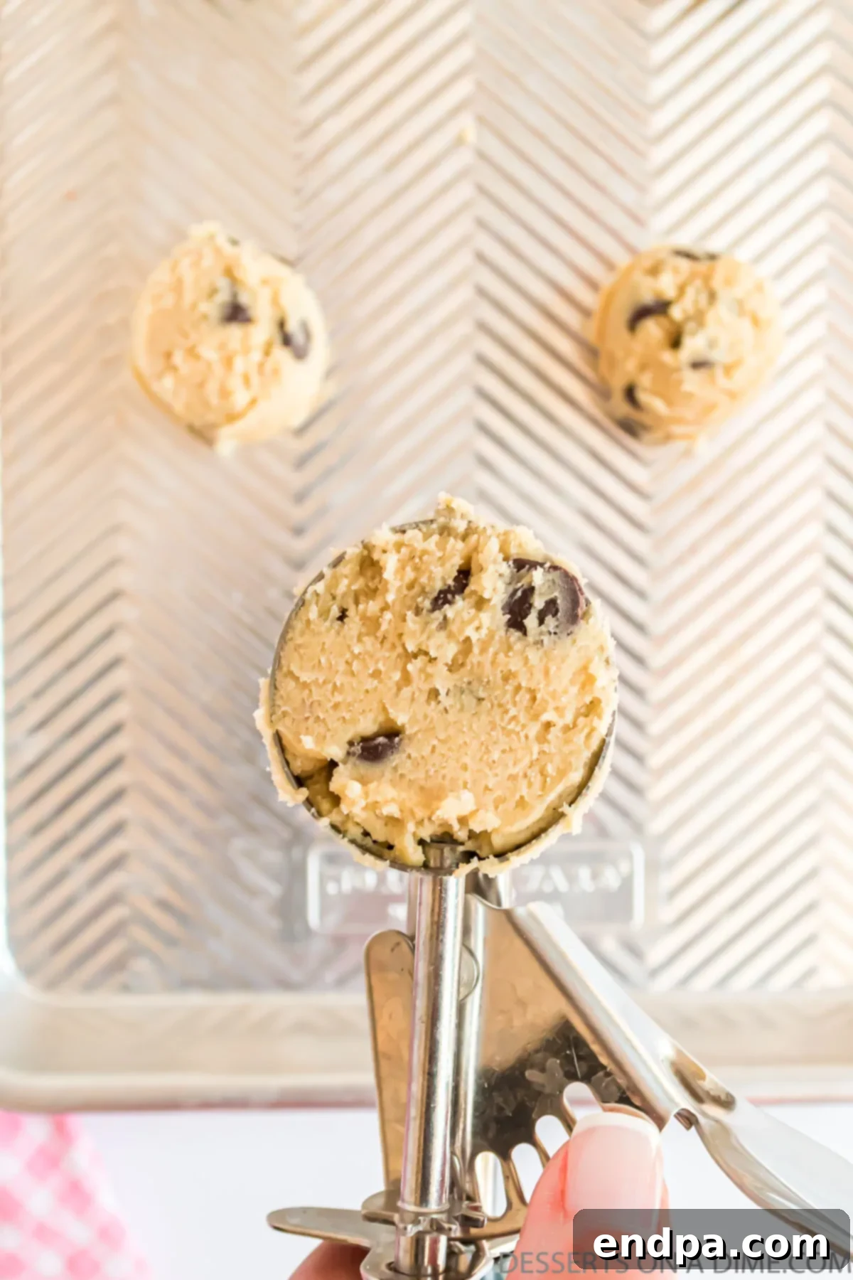 A scoop of chocolate chip cookie dough perfectly portioned and ready for baking.