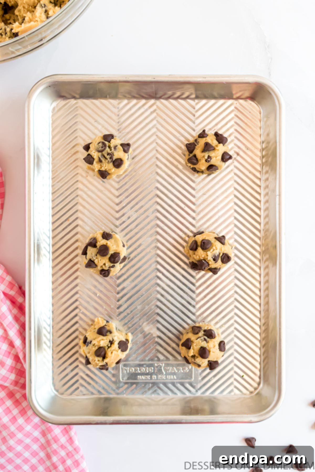 Freshly scooped cookie dough balls arranged on a baking sheet, spaced for even baking.