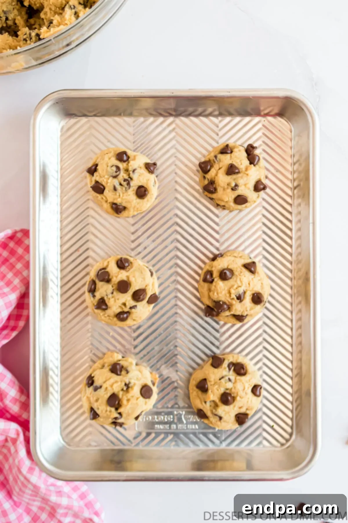 Warm cookies cooling on a baking sheet before being transferred to a wire rack.