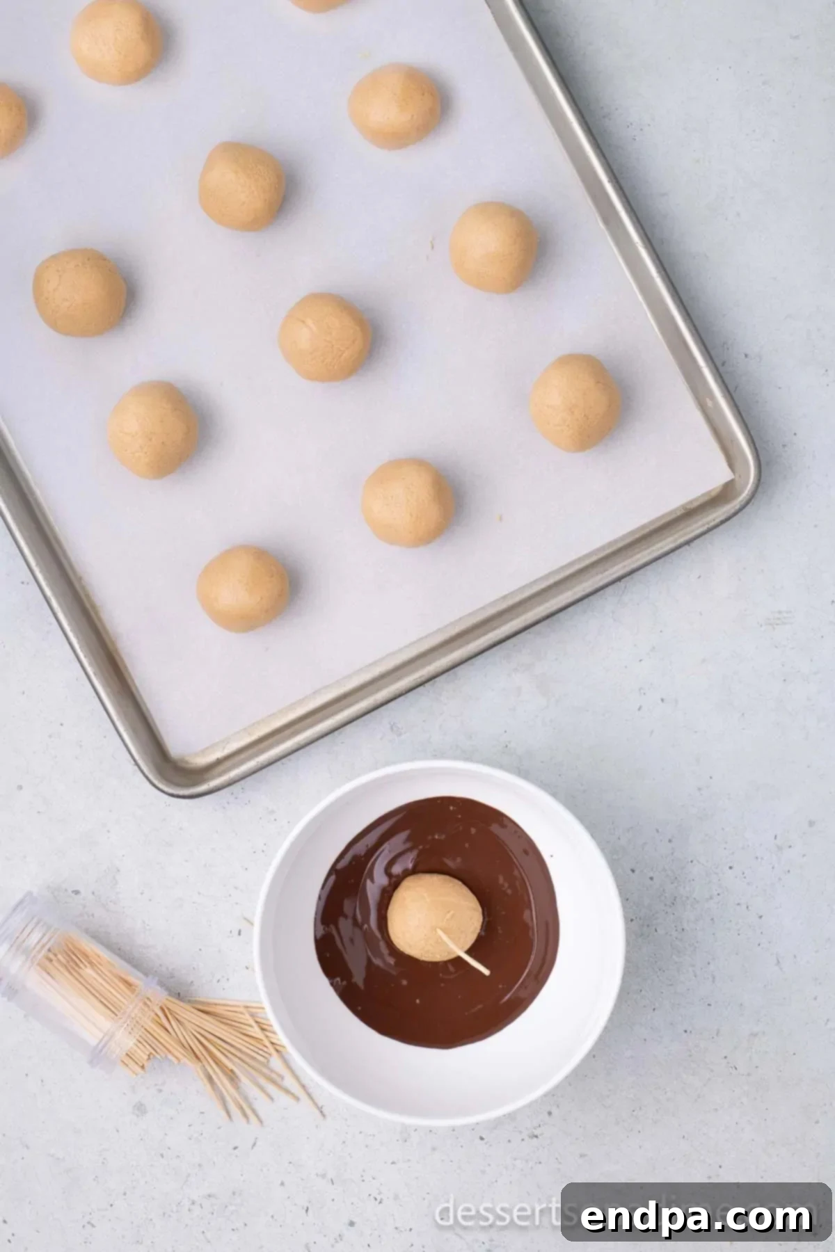 Buckeye Peanut Butter Delights 8 A peanut butter ball impaled on a toothpick is being dipped into a bowl of smooth, melted chocolate, showing the signature 'eye' of peanut butter left exposed.