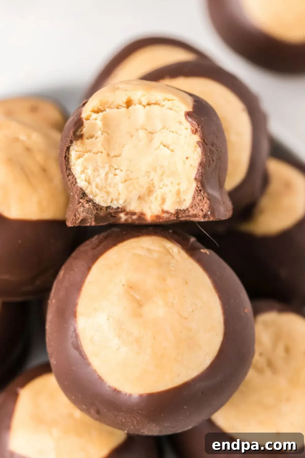Buckeye Peanut Butter Delights 10 A close-up stack of several finished Buckeye Peanut Butter Balls, showing their perfectly smooth chocolate coating and a small peanut butter eye, ready to be enjoyed.