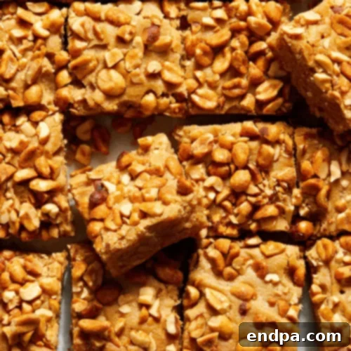 Chewy Honey and Peanut Butter Blondies, studded with peanuts and drizzled with honey.