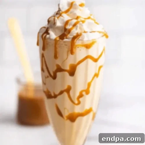 A tall glass of Dreamy Caramel Milkshake, topped with whipped cream and a generous caramel drizzle.