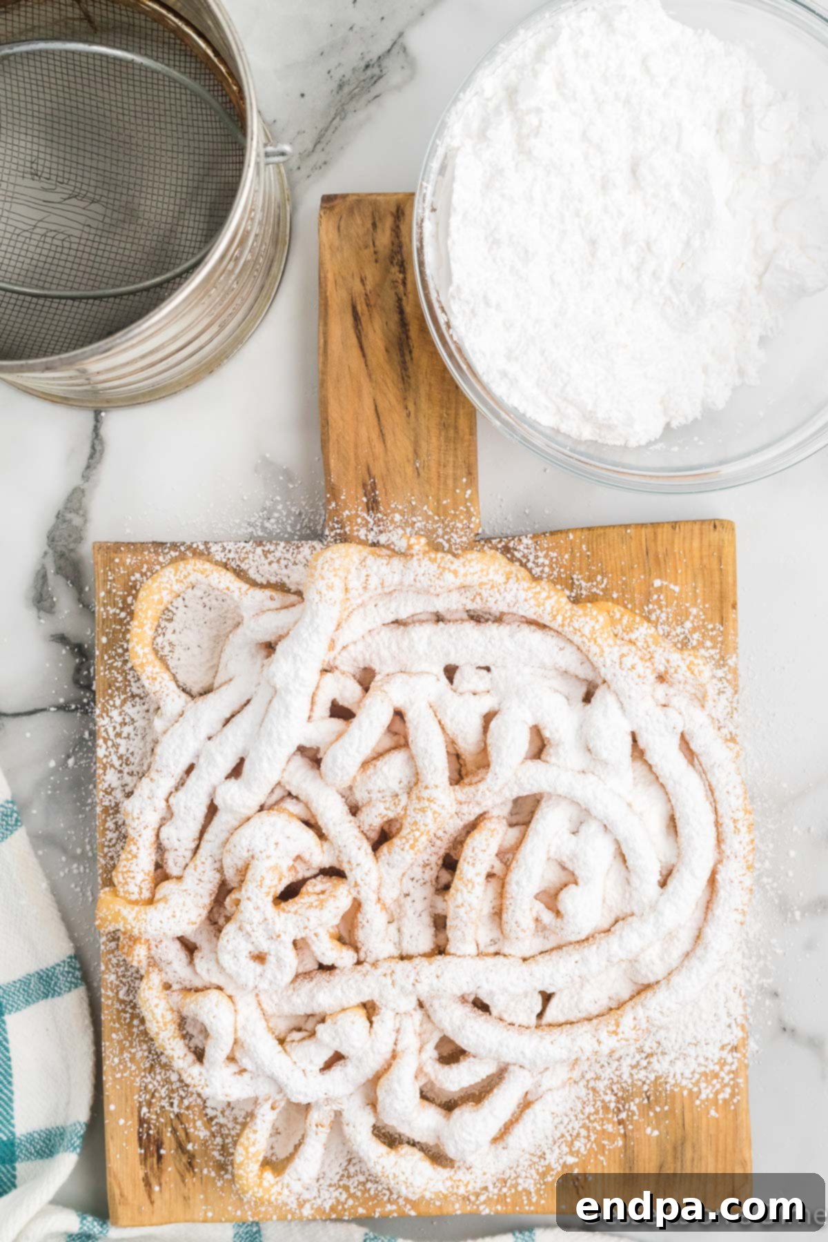 A warm funnel cake generously dusted with powdered sugar, ready to be served as a delightful treat.