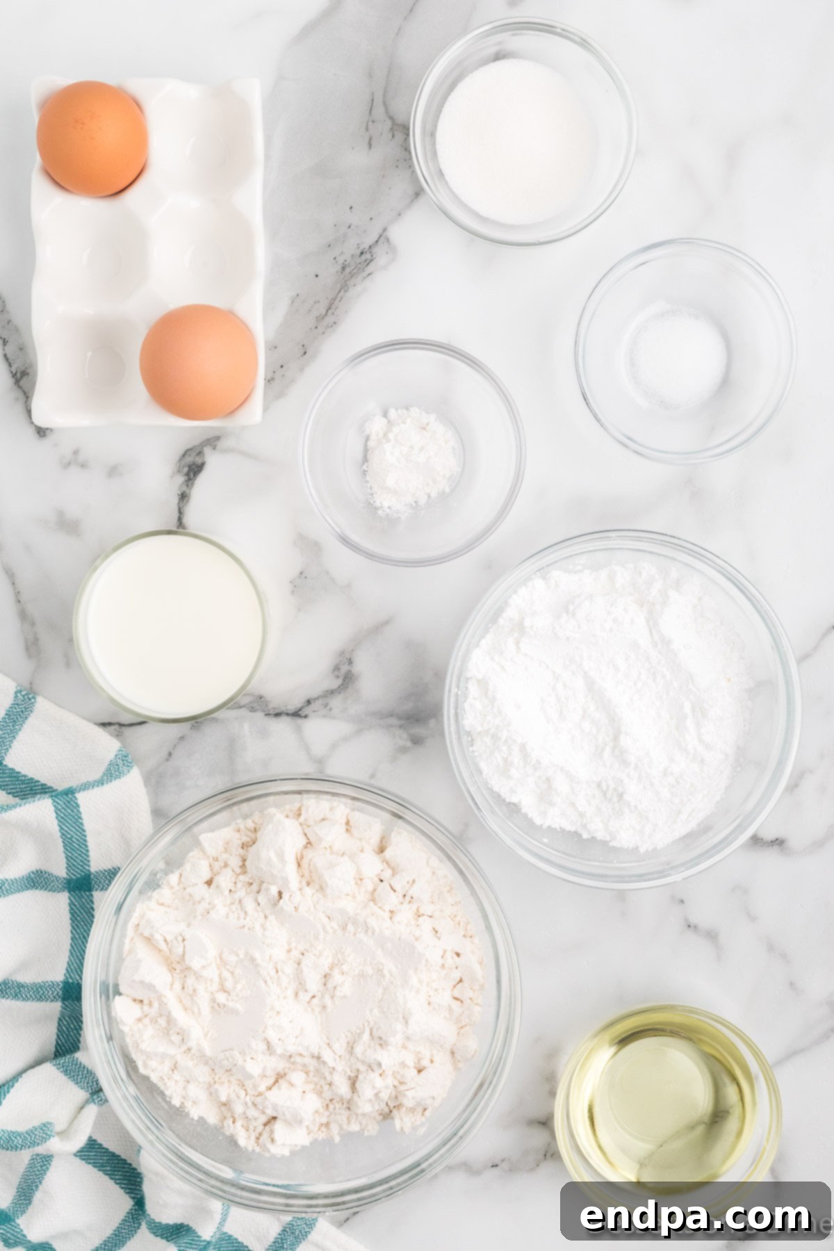 A collection of essential ingredients for making funnel cake, including all-purpose flour, granulated sugar, baking powder, salt, milk, large eggs, and vegetable oil.