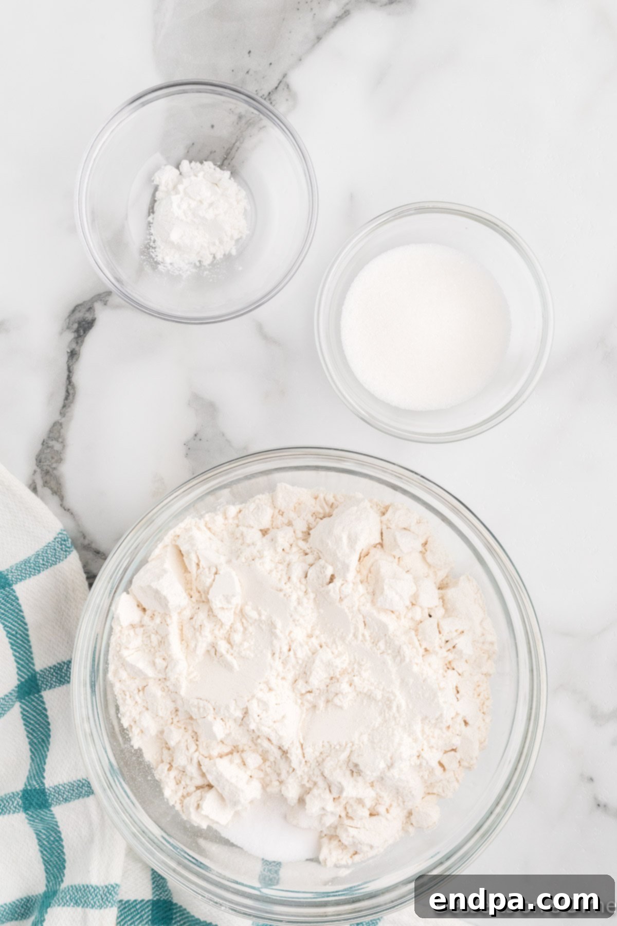 Dry ingredients for funnel cake batter, including flour, sugar, baking powder, and salt, measured into a large mixing bowl.