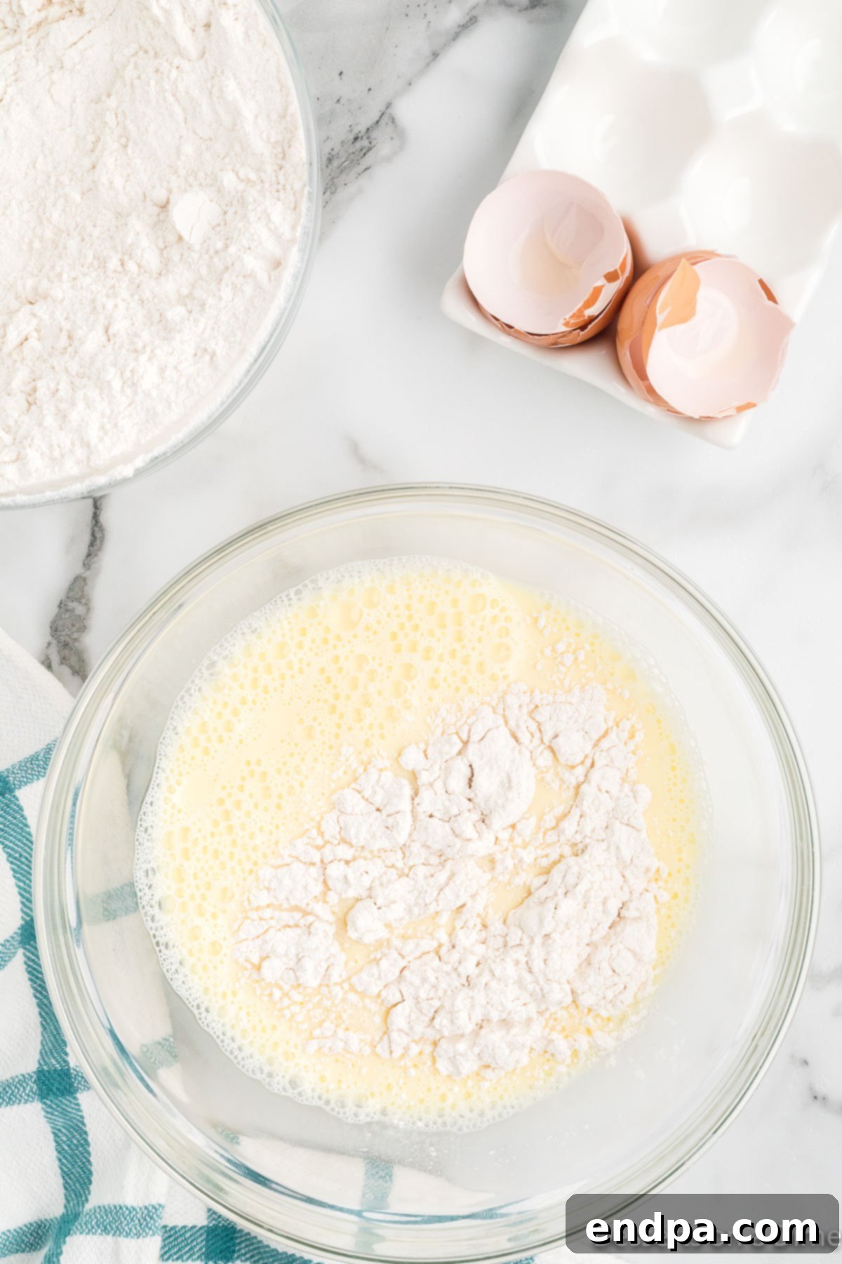 The process of combining wet and dry ingredients for funnel cake batter in a single mixing bowl.