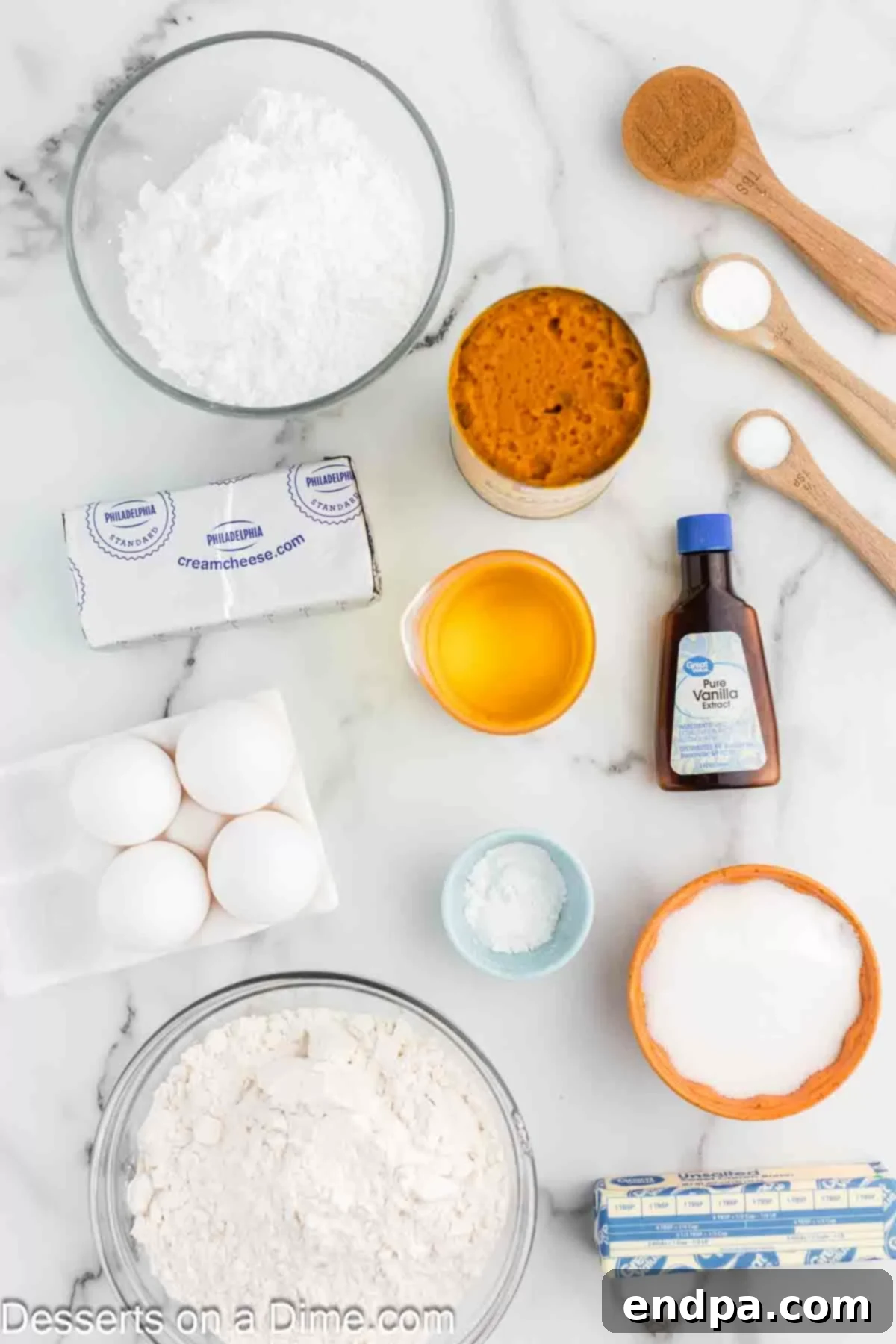 A vibrant flat lay photograph showcasing all the meticulously arranged ingredients required for both the pumpkin cake and its cream cheese frosting. The components include all-purpose flour, a can of pure pumpkin puree, large eggs, vegetable oil, granulated sugar, baking powder, baking soda, pumpkin pie spice, salt, cream cheese, butter, vanilla extract, and powdered sugar, all artfully displayed.