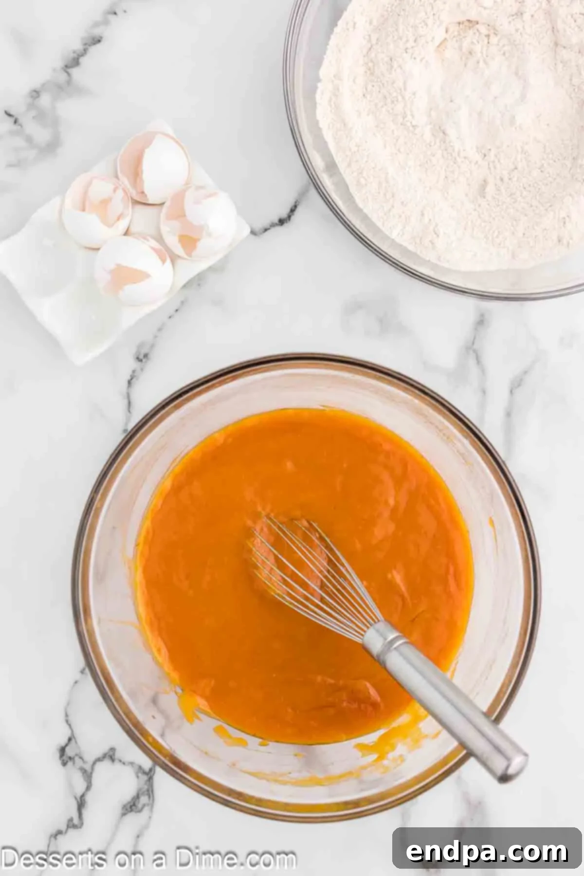 In a separate, medium-sized bowl, the wet ingredients destined for the pumpkin cake—granulated sugar, vegetable oil, and creamy pure pumpkin puree—are being skillfully whisked together until the mixture achieves a smooth, harmonious, and fully integrated consistency.