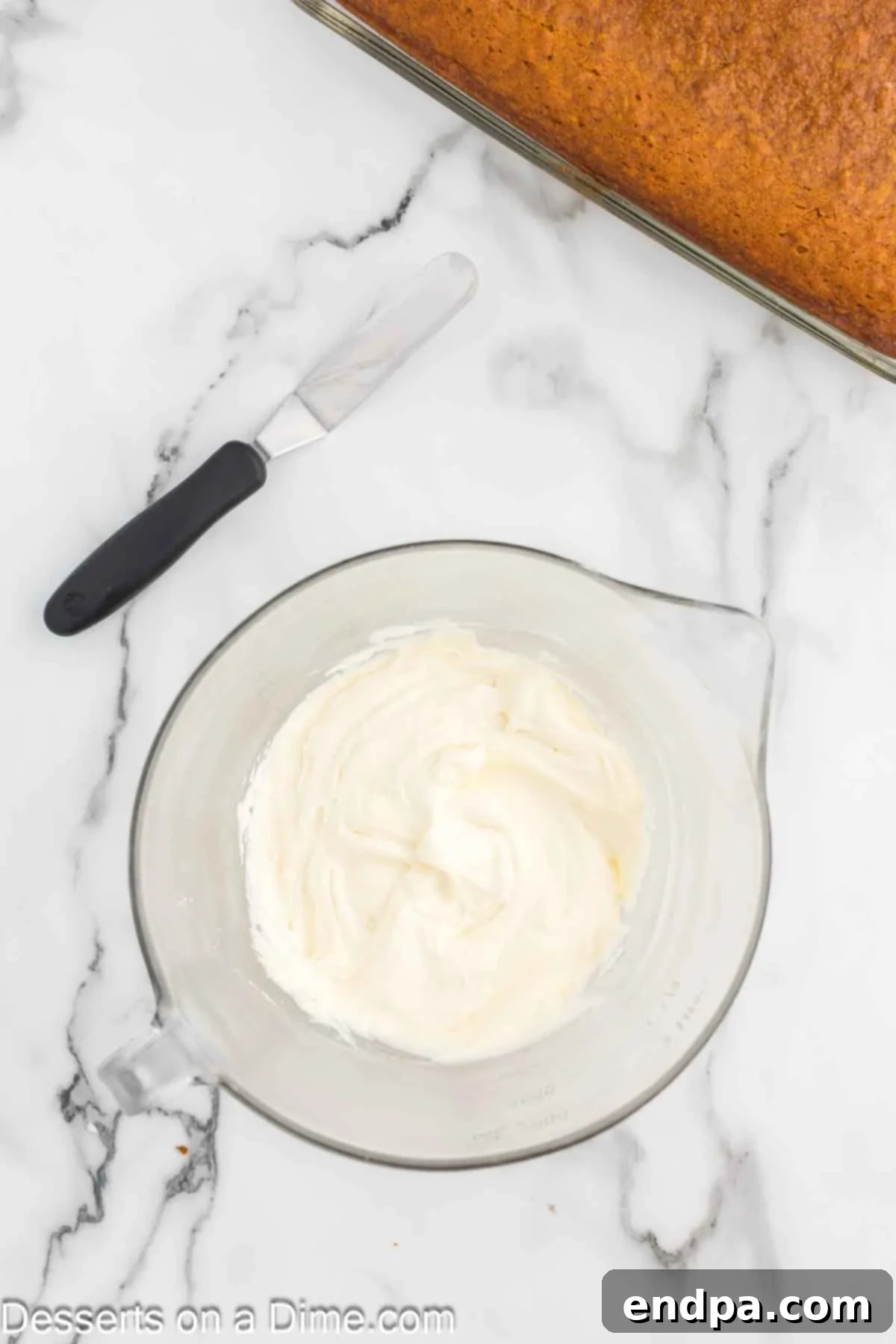 Softened cream cheese and room temperature butter are being vigorously beaten together in a large mixing bowl using an electric mixer. The mixture is transforming into a light, airy, and fluffy consistency, ready for the next stages of frosting preparation.