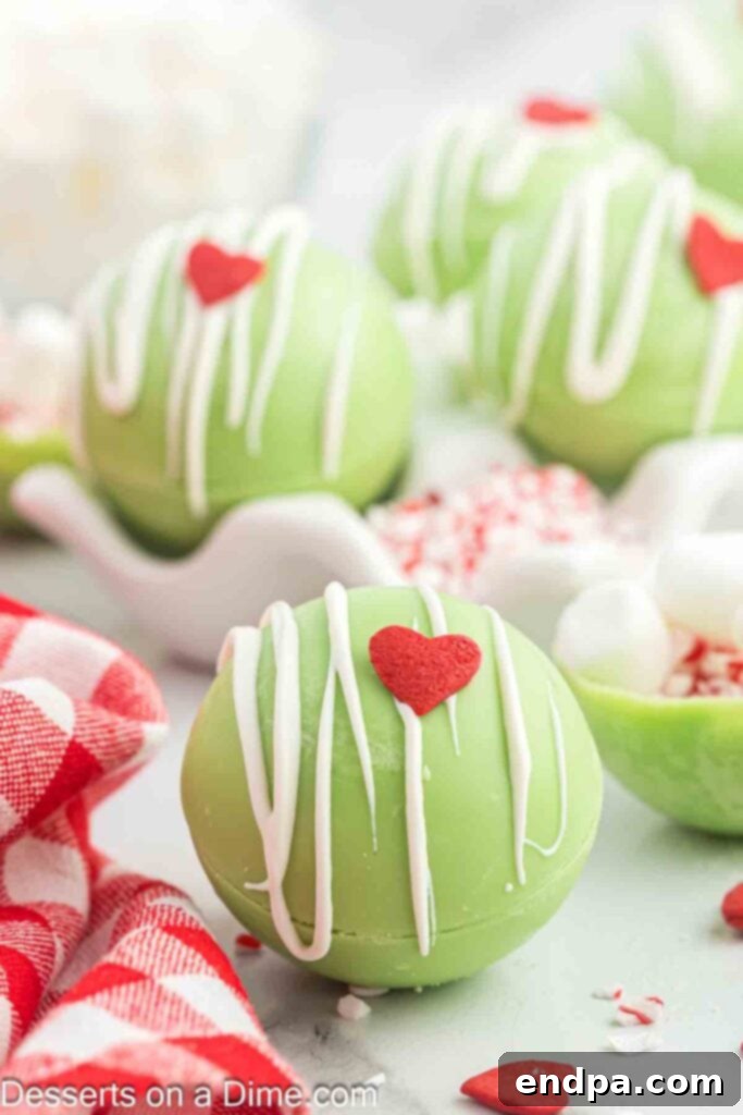 Grinchmas Hot Cocoa Bombs 2 Grinch Hot Chocolate Bombs ready to enjoy with a festive backdrop.