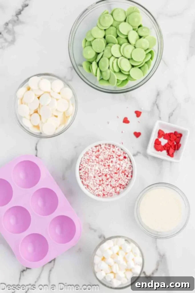 Grinchmas Hot Cocoa Bombs 3 A flat lay of ingredients including green candy melts, marshmallows, and hot chocolate mix.