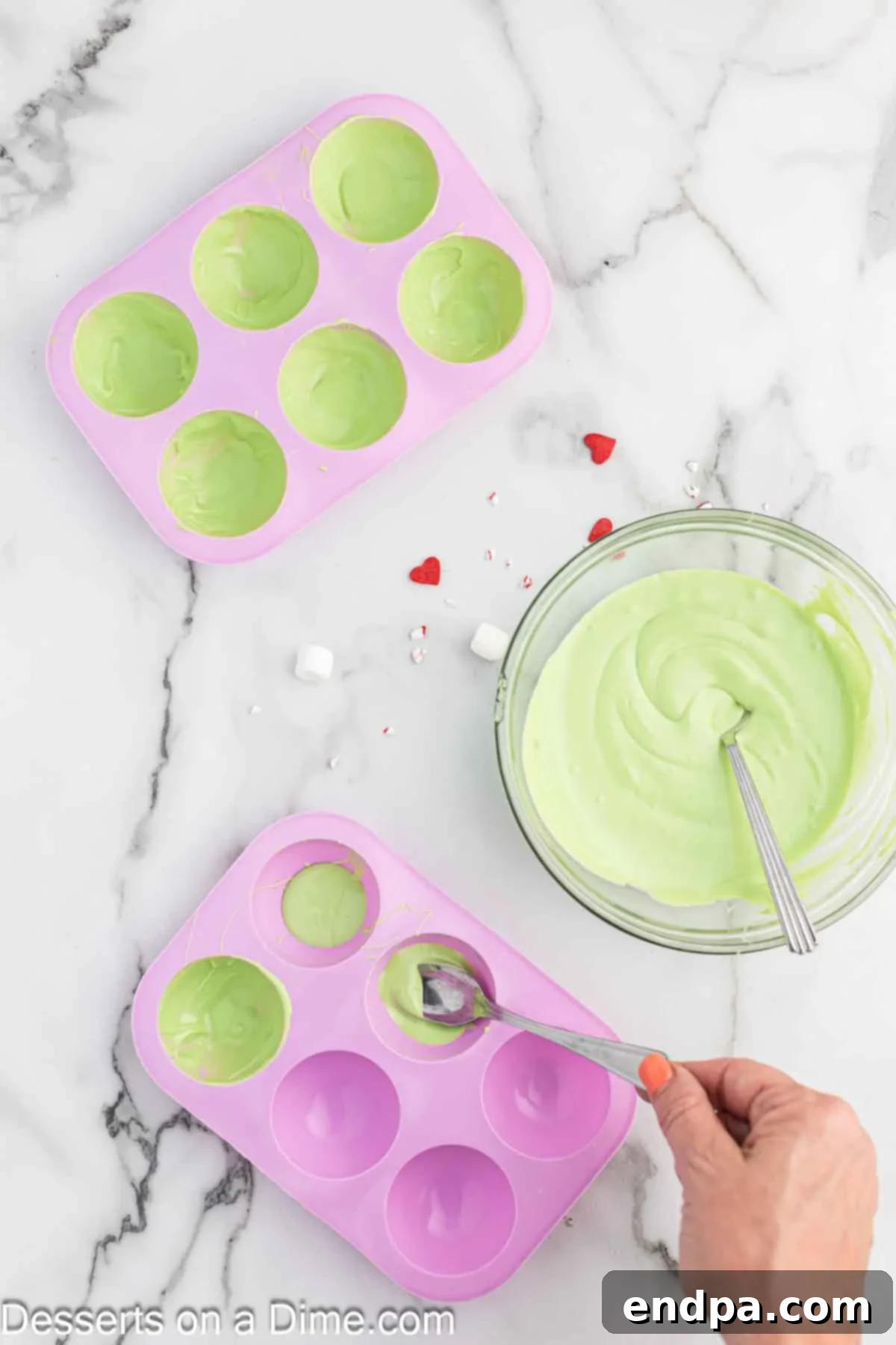Grinchmas Hot Cocoa Bombs 4 Melted green candy melts being smoothed into a silicone mold.