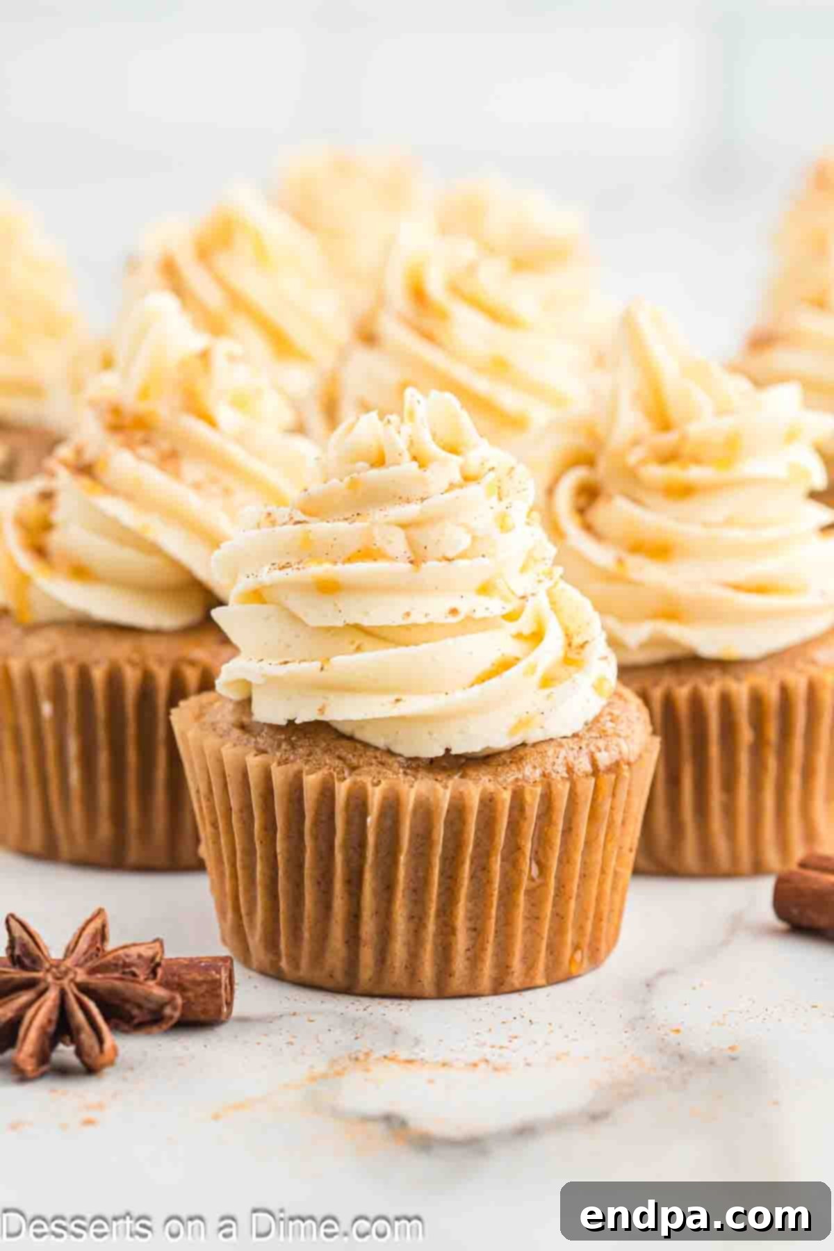 Sticky Caramel Apple Swirl Cupcakes 2 Beautifully frosted caramel apple cupcakes ready to be enjoyed, garnished with a drizzle of caramel.