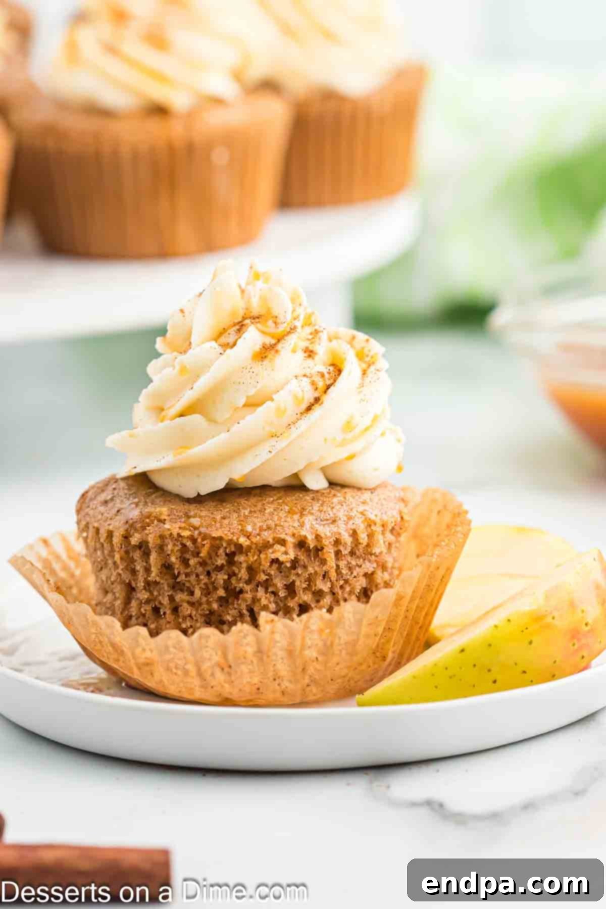 Sticky Caramel Apple Swirl Cupcakes 11 A tray of beautifully frosted caramel apple cupcakes, each drizzled with caramel sauce.