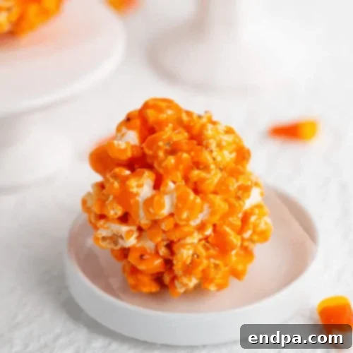 Vibrant orange Candy Corn Popcorn Balls, coated in a sweet glaze.