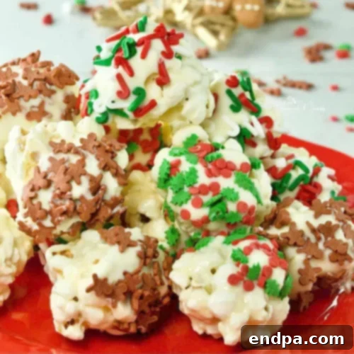 White Chocolate Popcorn Balls, coated in white chocolate and decorated with festive sprinkles.
