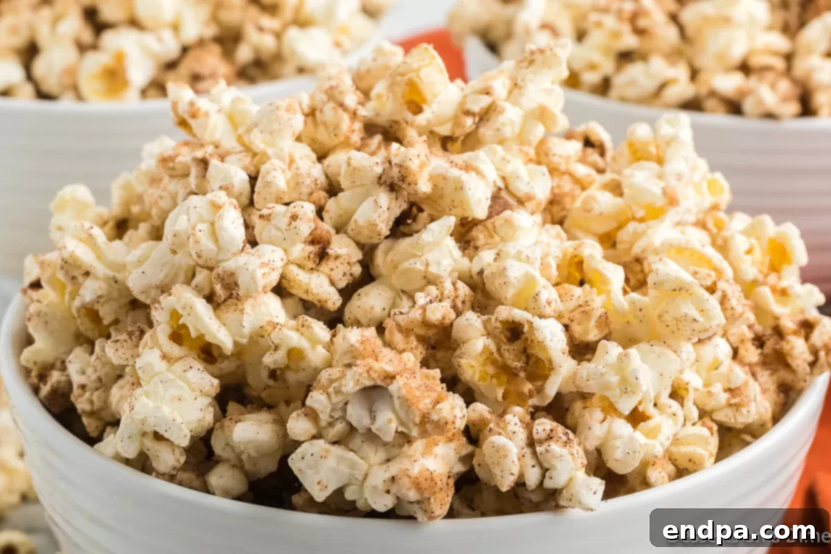 A vibrant bowl of Pumpkin Spice Popcorn, featuring golden popcorn kernels coated in a rich pumpkin spice glaze, perfect for a cozy fall snack.