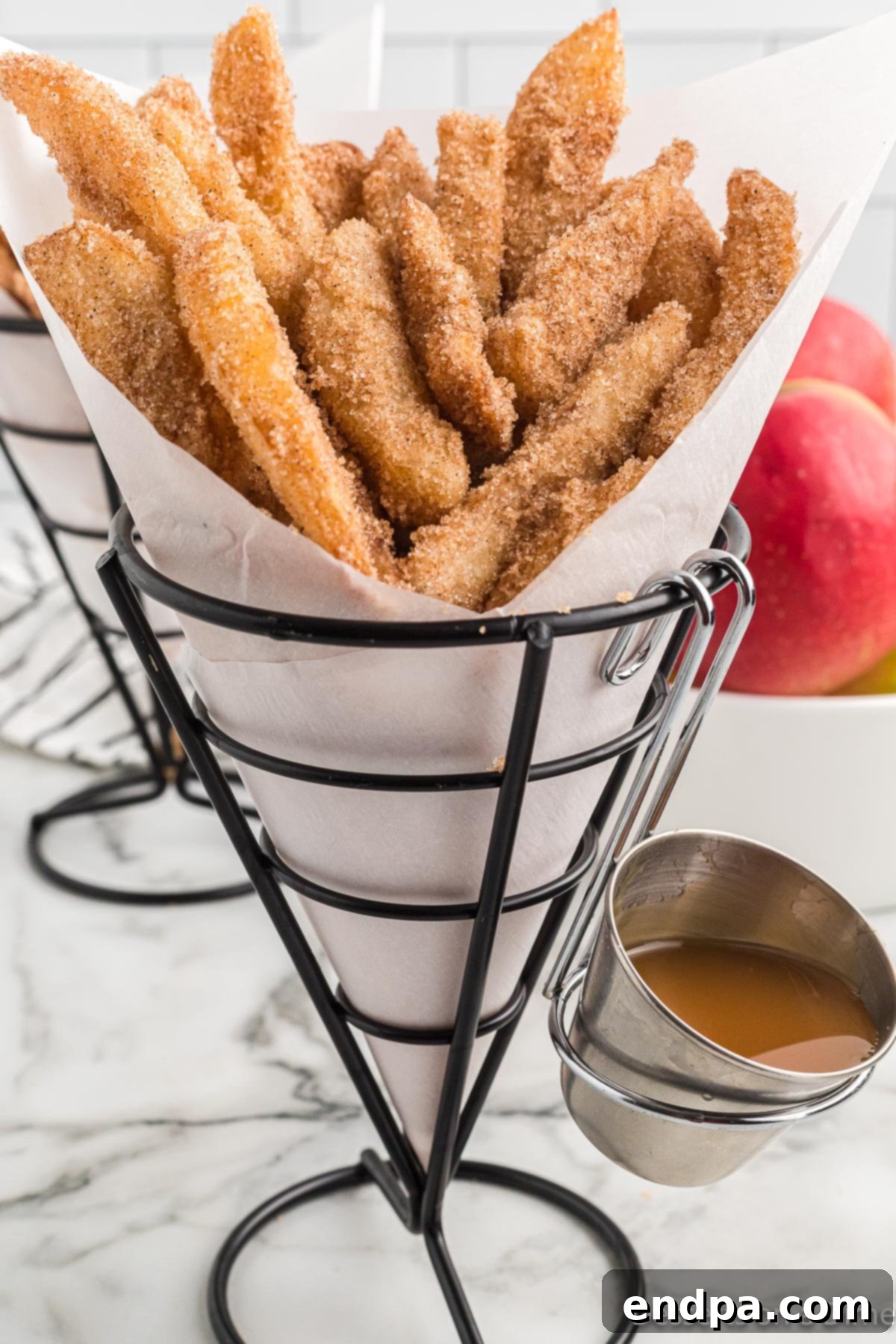 Crispy homemade Apple Fries ready to enjoy with a generous side of creamy caramel sauce.