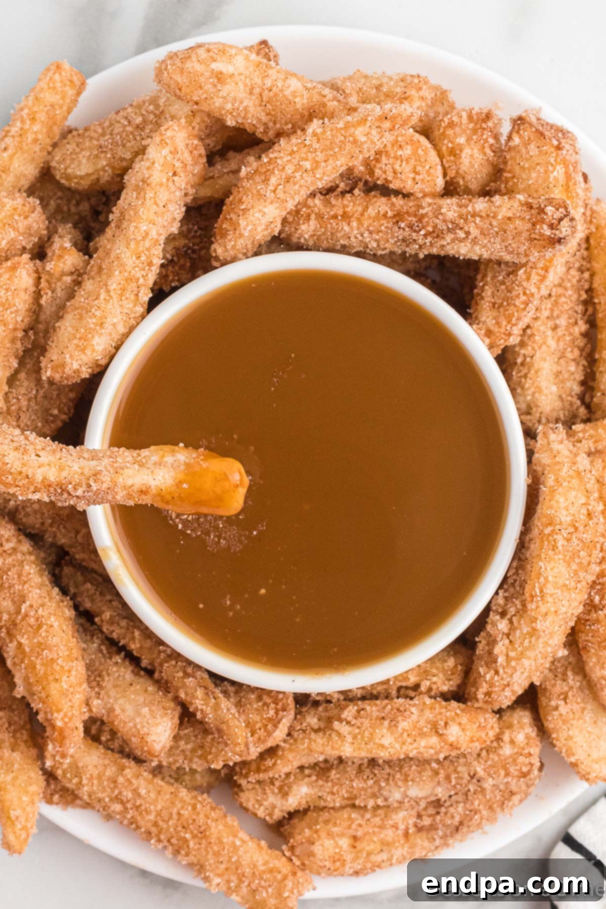 Platter of cinnamon sugar apple fries served with a ramekin of caramel dipping sauce.