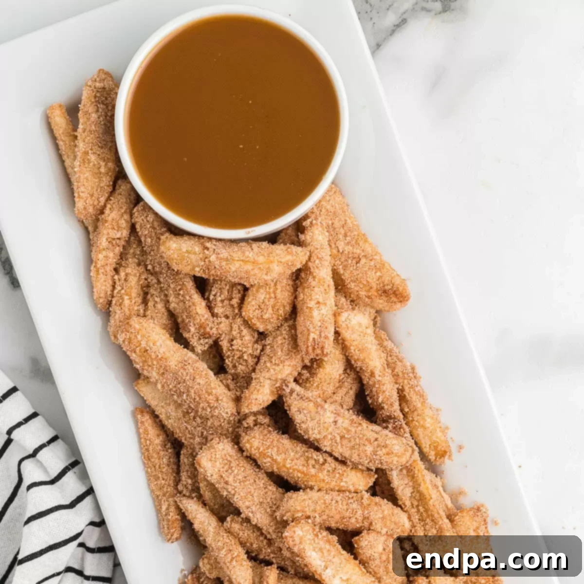 A vibrant close-up of crispy Apple Fries, artfully arranged and ready for dipping in caramel sauce.