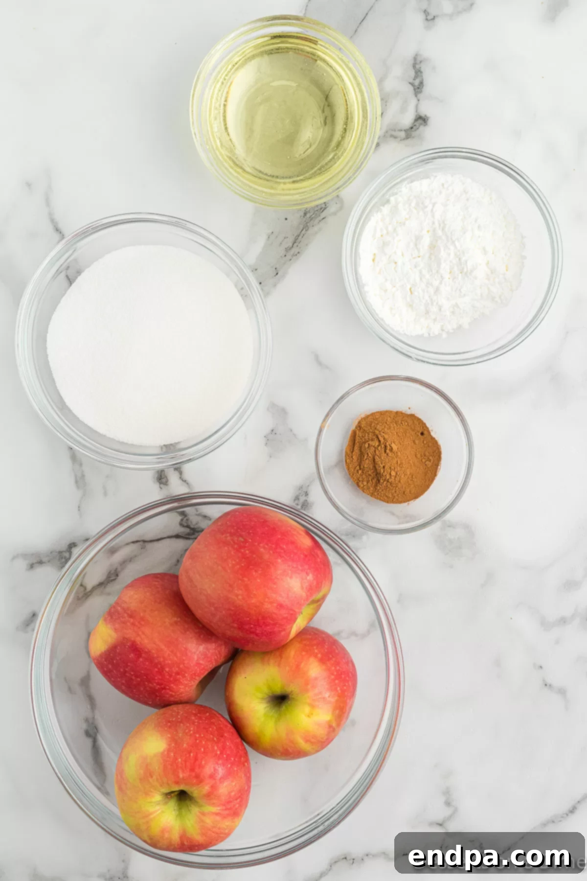 Ingredients for making homemade apple fries: fresh apples, cooking oil, cornstarch, granulated sugar, ground cinnamon, and a jar of caramel sauce.