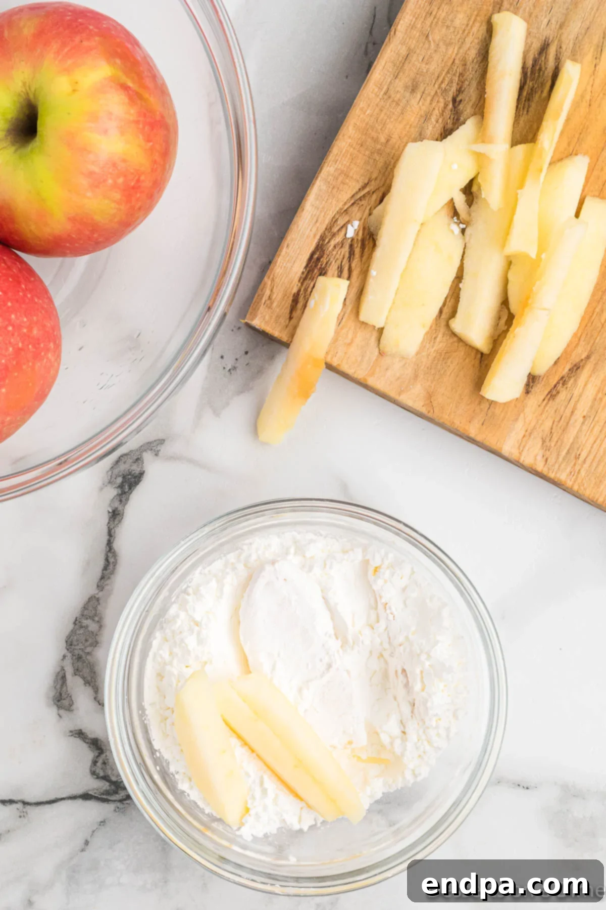 Apple slices tossed in a bowl with cornstarch, ensuring an even coating.