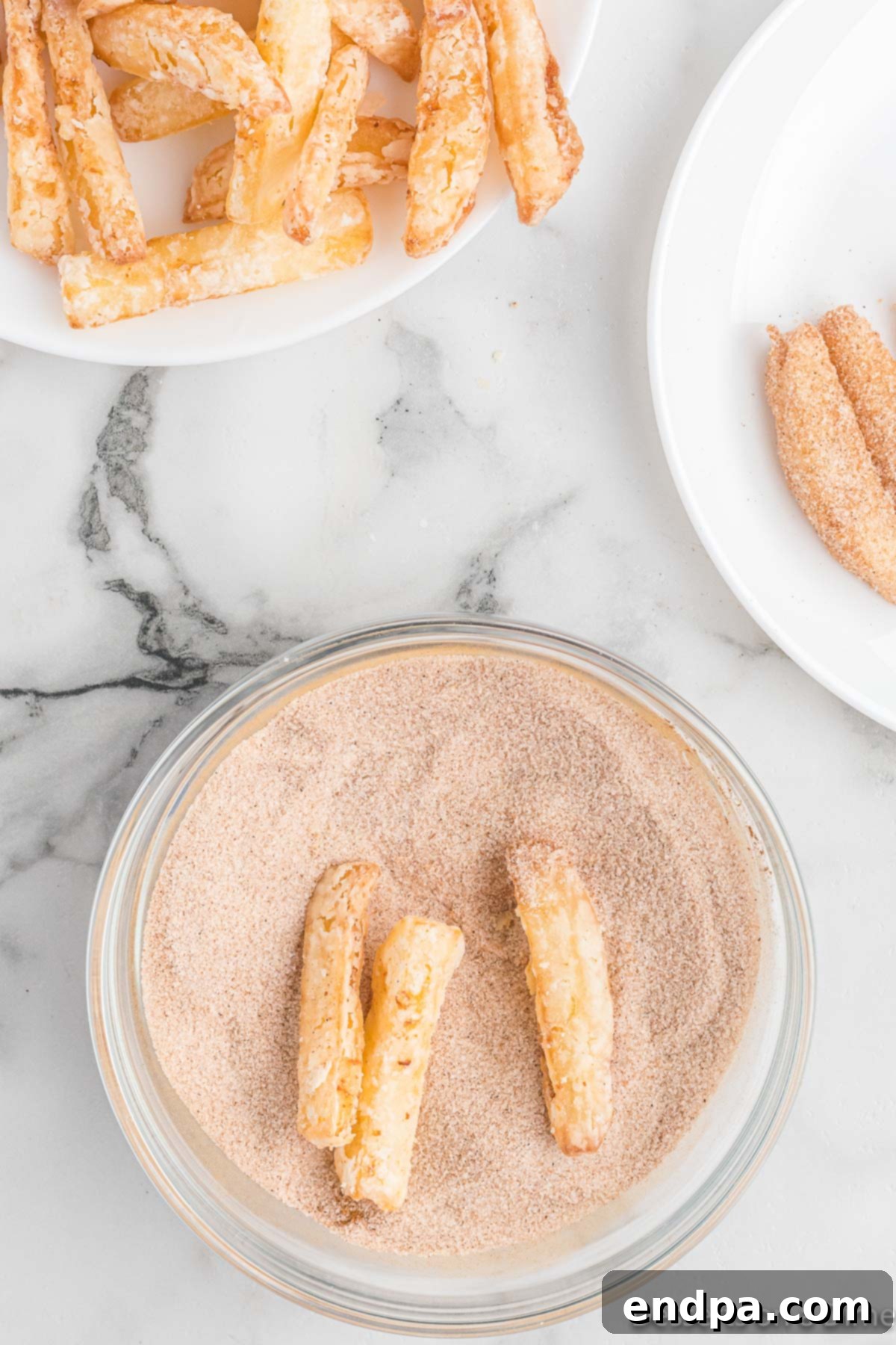 Hot apple fries being tossed in a bowl of cinnamon sugar, ensuring a thorough coating.