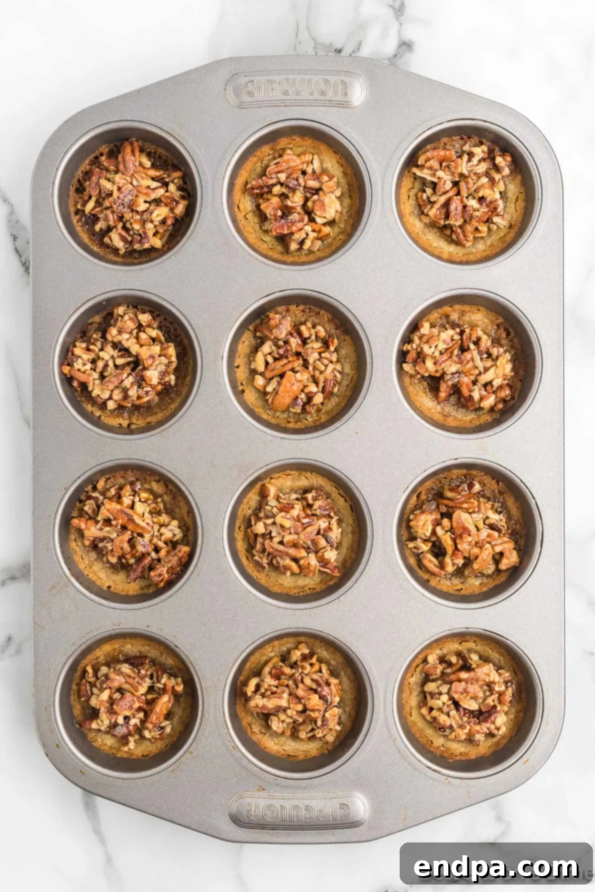 Pecan Pie in a Cookie 7 Freshly baked pecan pie cookies cooling in the muffin pan, with a beautiful golden-brown finish.