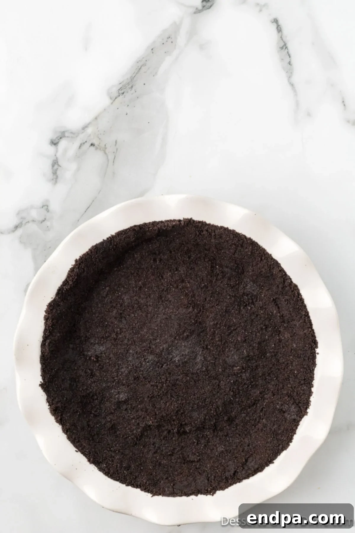 Decadent No Bake Nutella Cheesecake 6 Oreo cookie mixture pressed firmly into the bottom and sides of a 9-inch pie plate, forming the cheesecake crust.