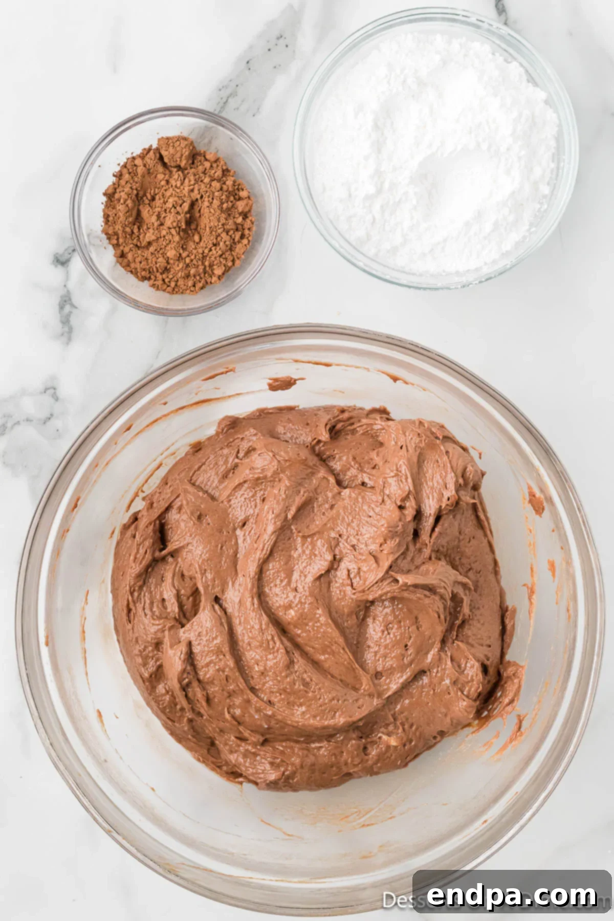Decadent No Bake Nutella Cheesecake 7 Cream cheese and Nutella being beaten together in a large mixing bowl with an electric hand mixer, creating a smooth, dark brown mixture.