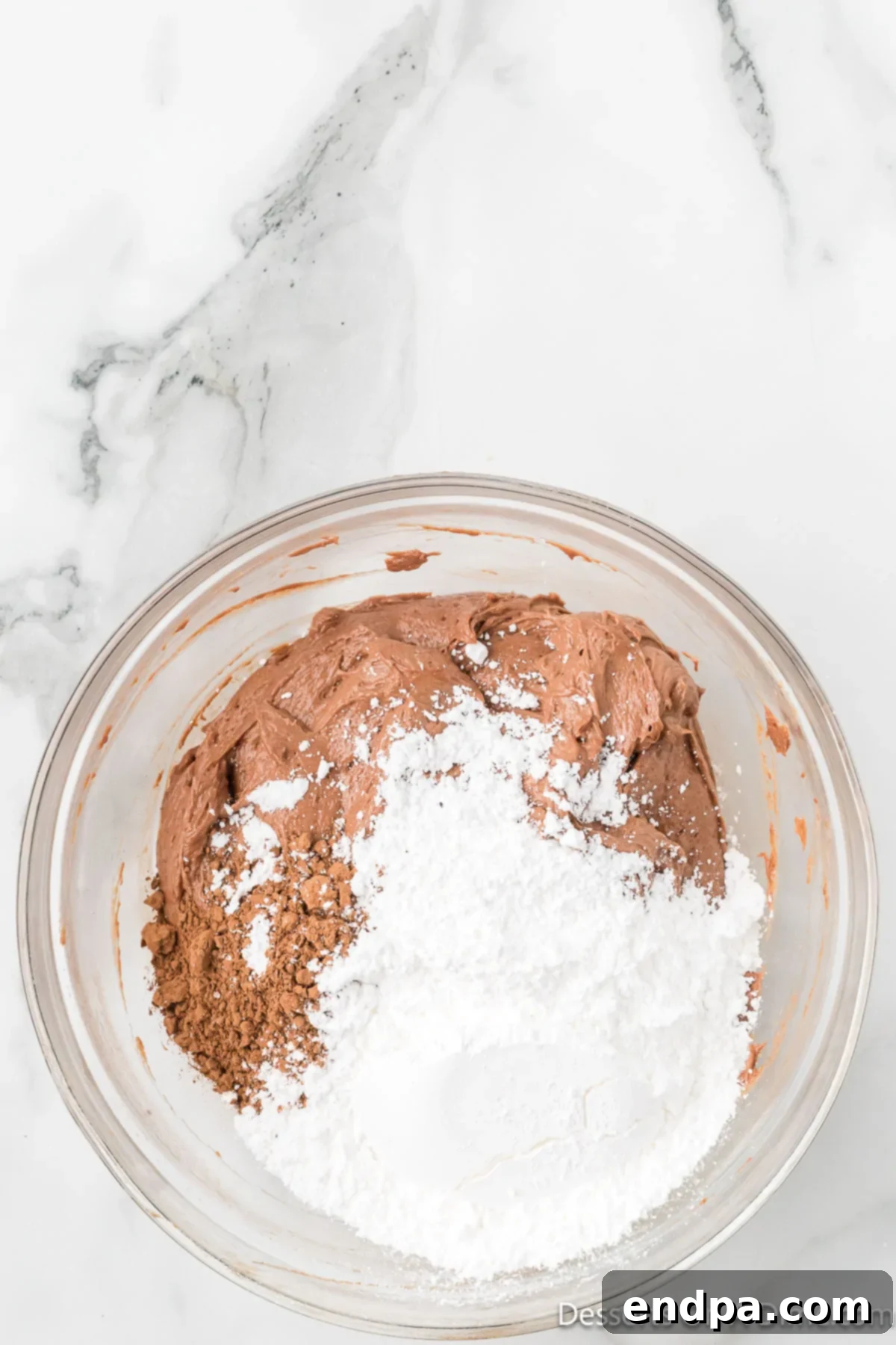 Decadent No Bake Nutella Cheesecake 8 Cocoa powder and sifted powdered sugar being added to the Nutella and cream cheese mixture in a bowl, ready to be combined.