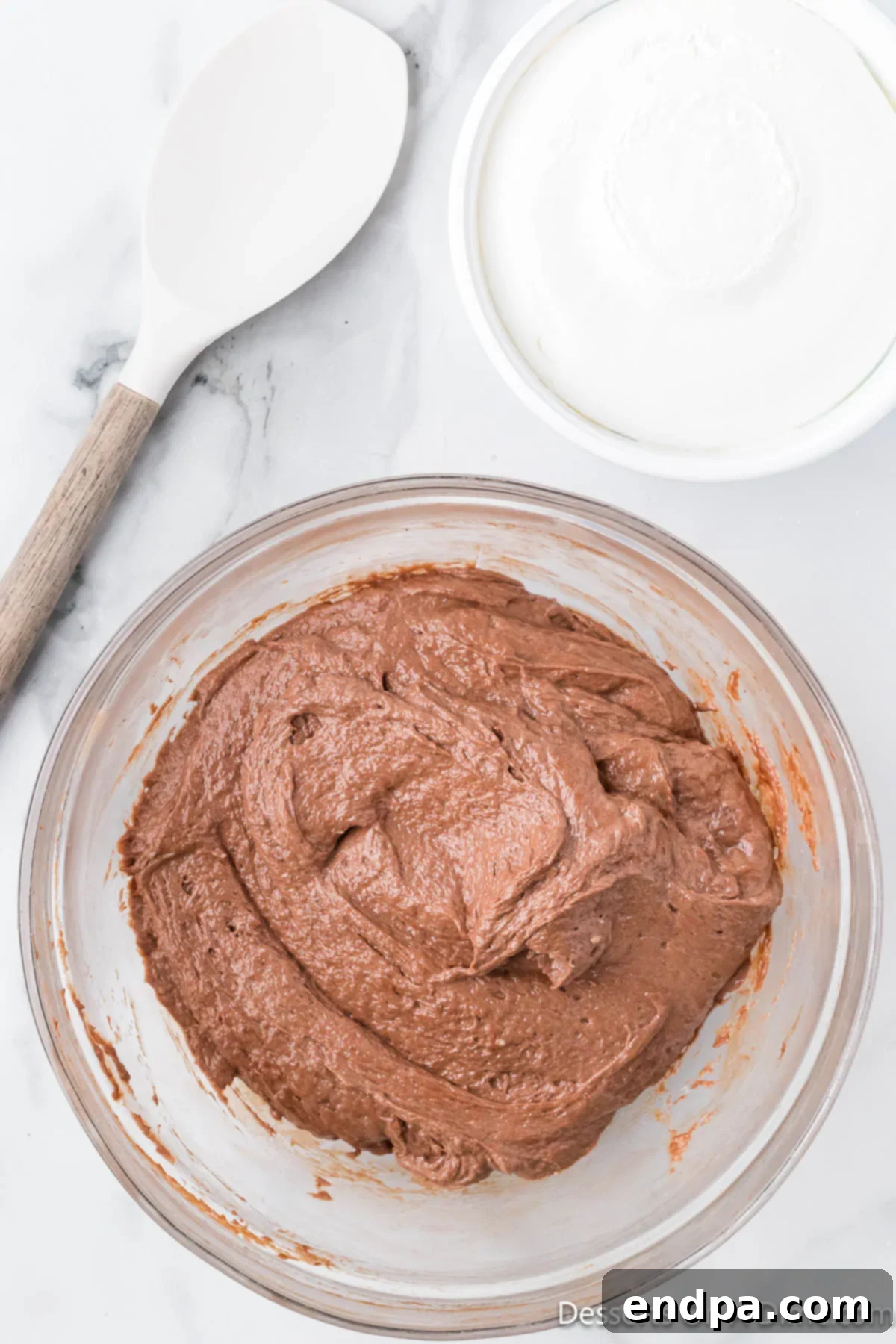 Decadent No Bake Nutella Cheesecake 9 Light whipped topping being gently folded into the rich Nutella and cream cheese mixture in a bowl with a spatula, creating a lighter filling.