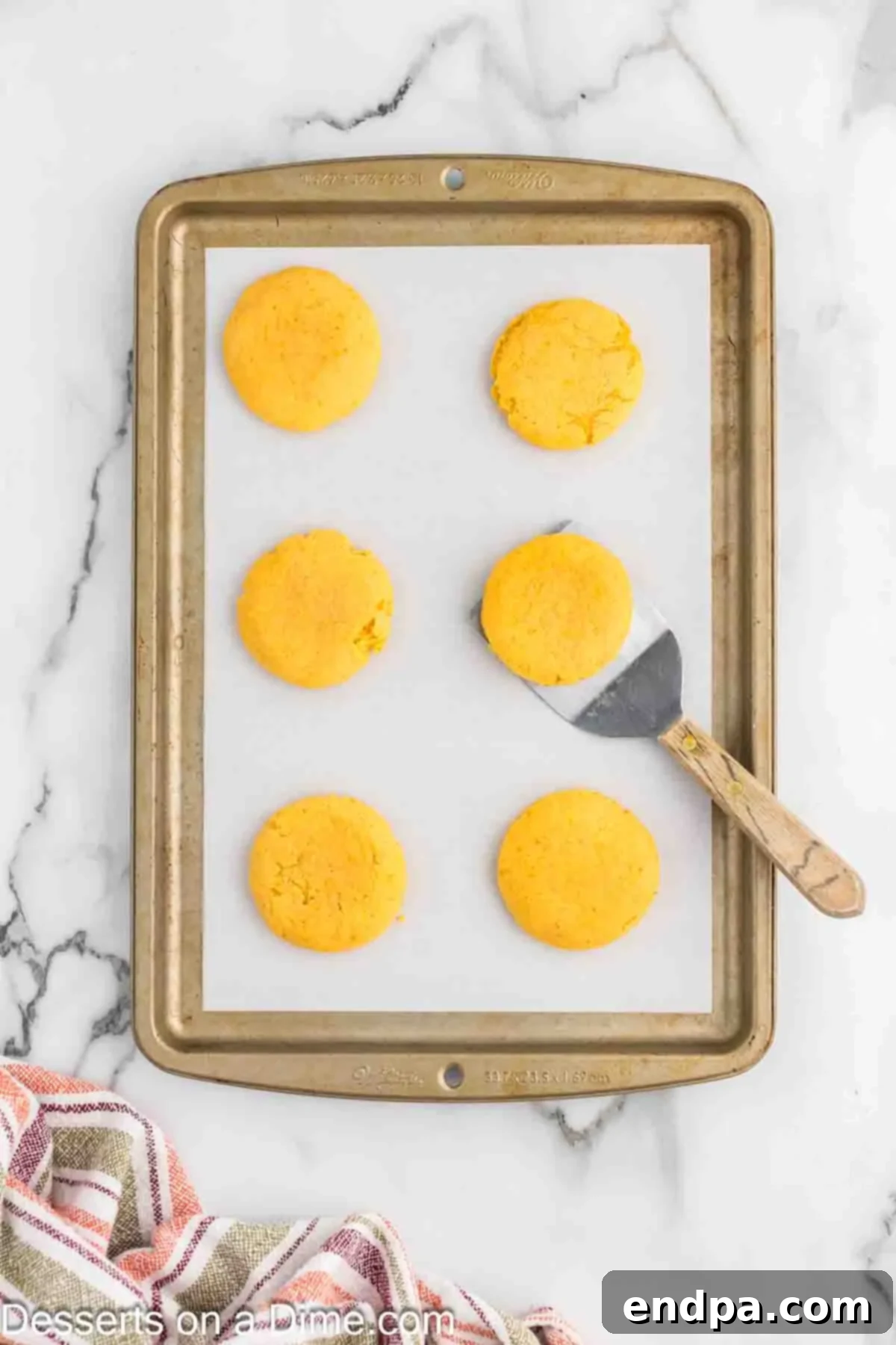Freshly baked pumpkin sugar cookies cooling on the baking sheet, indicating they are ready to be moved to a wire rack for complete cooling.